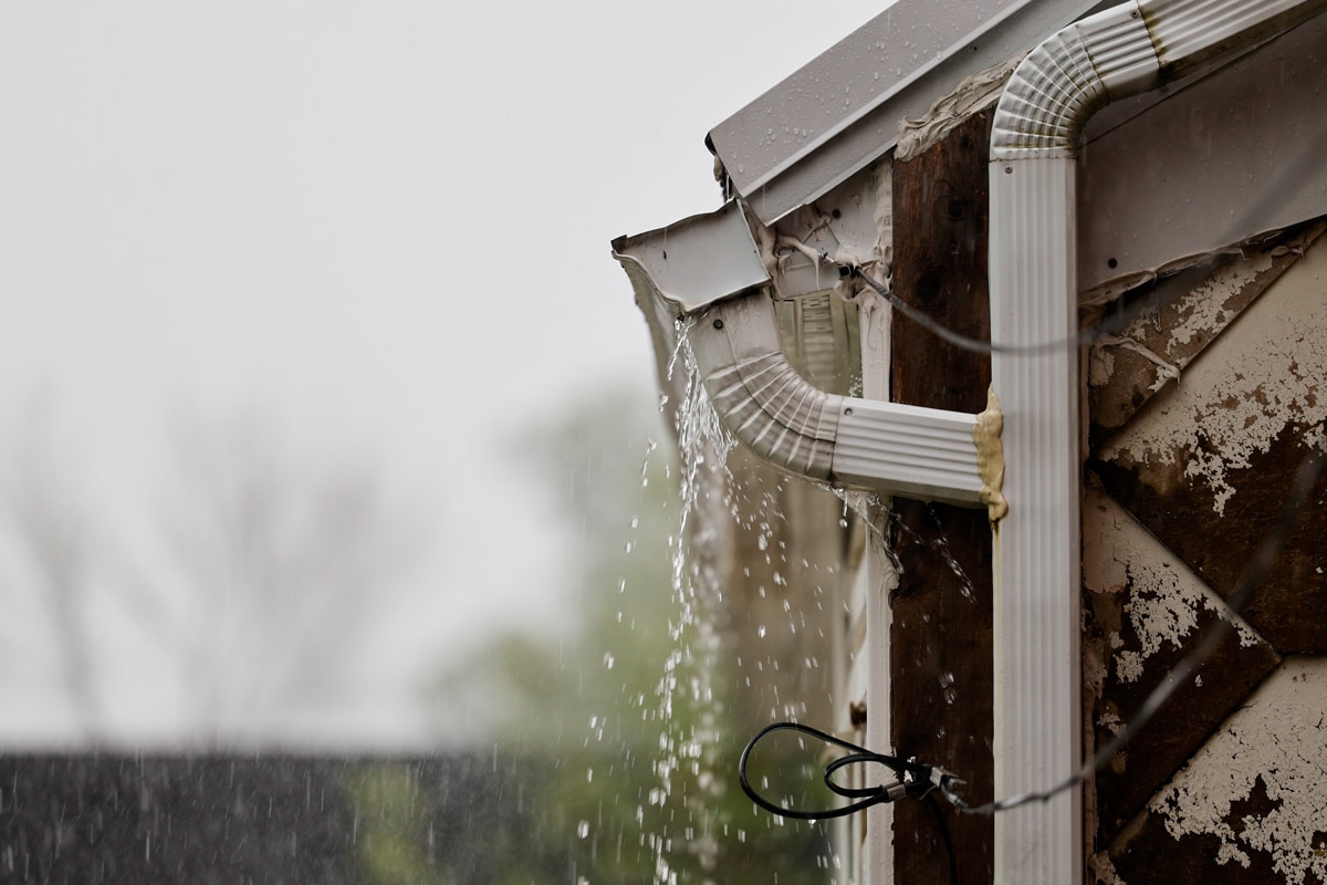Gouttière brisée qui déborde sous la pluie causant des dommages à la façade d'une maison, St-Léonard-d'Aston.