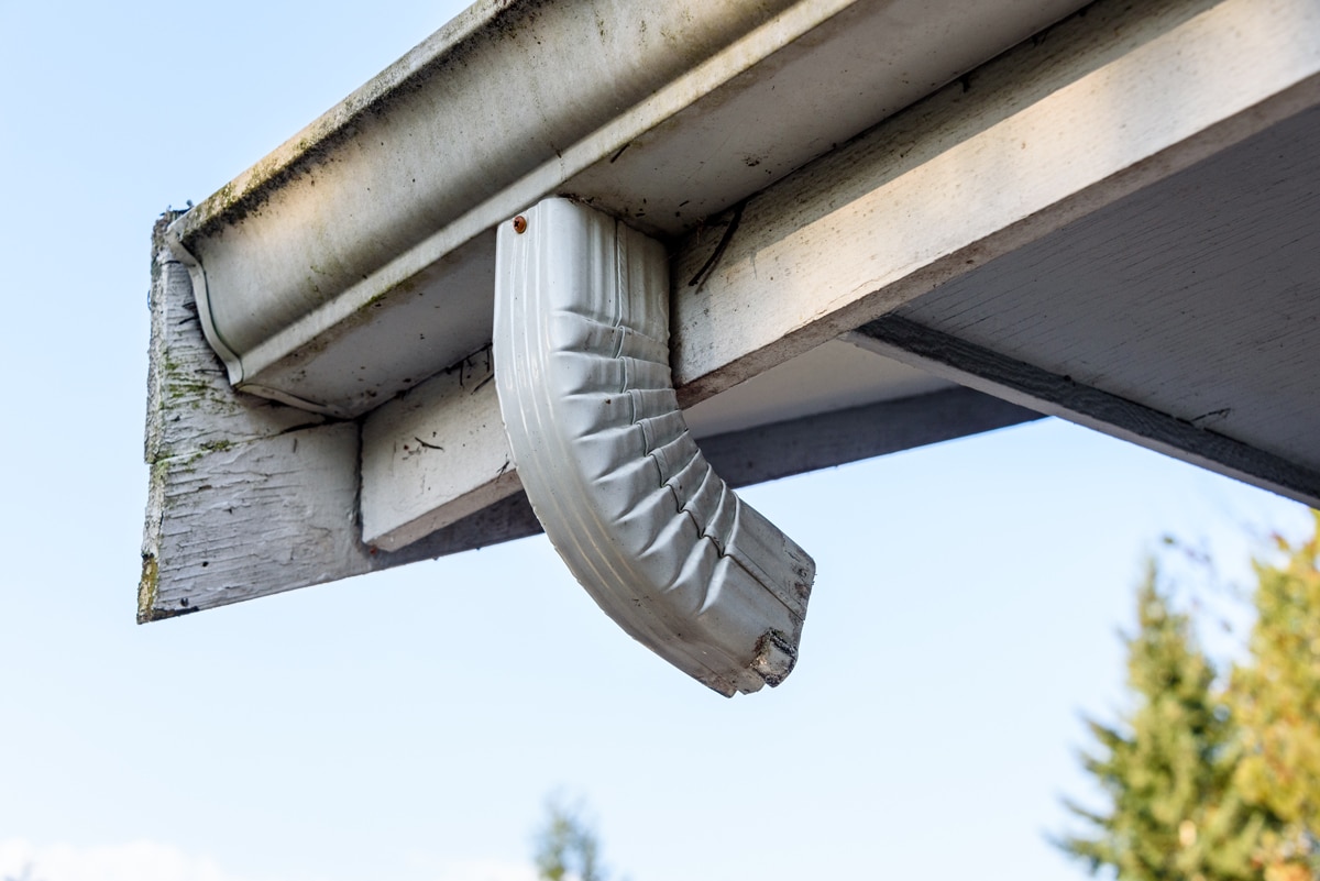 Gouttière et coude de descente pluviale en aluminium blanc endommagés nécessitant un remplacement, Montérégie.